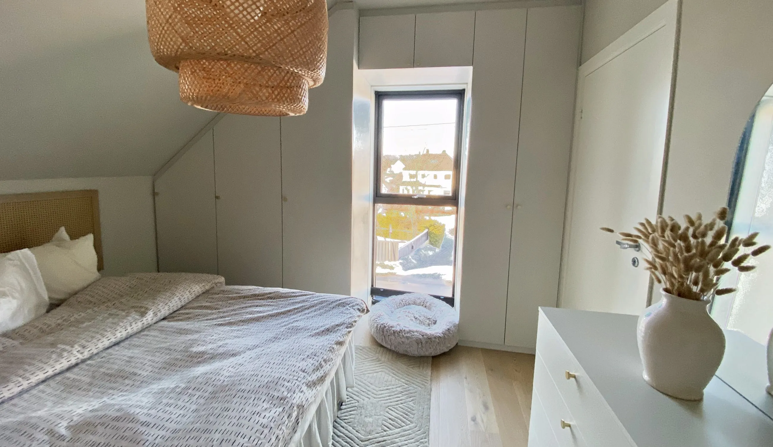 Lyst loftssoverom med garderobe bygget etter skråtaket, ved siden av vinduet