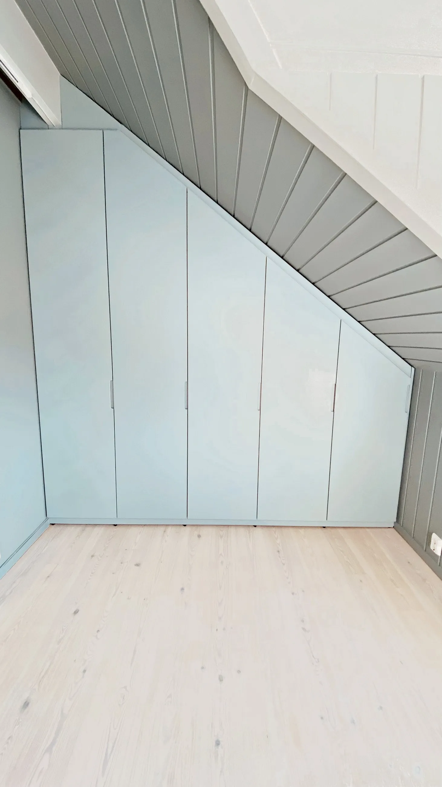 Skråtaksgarderobe i mintgrønt bygget etter takvinkelen, med glatte fronter